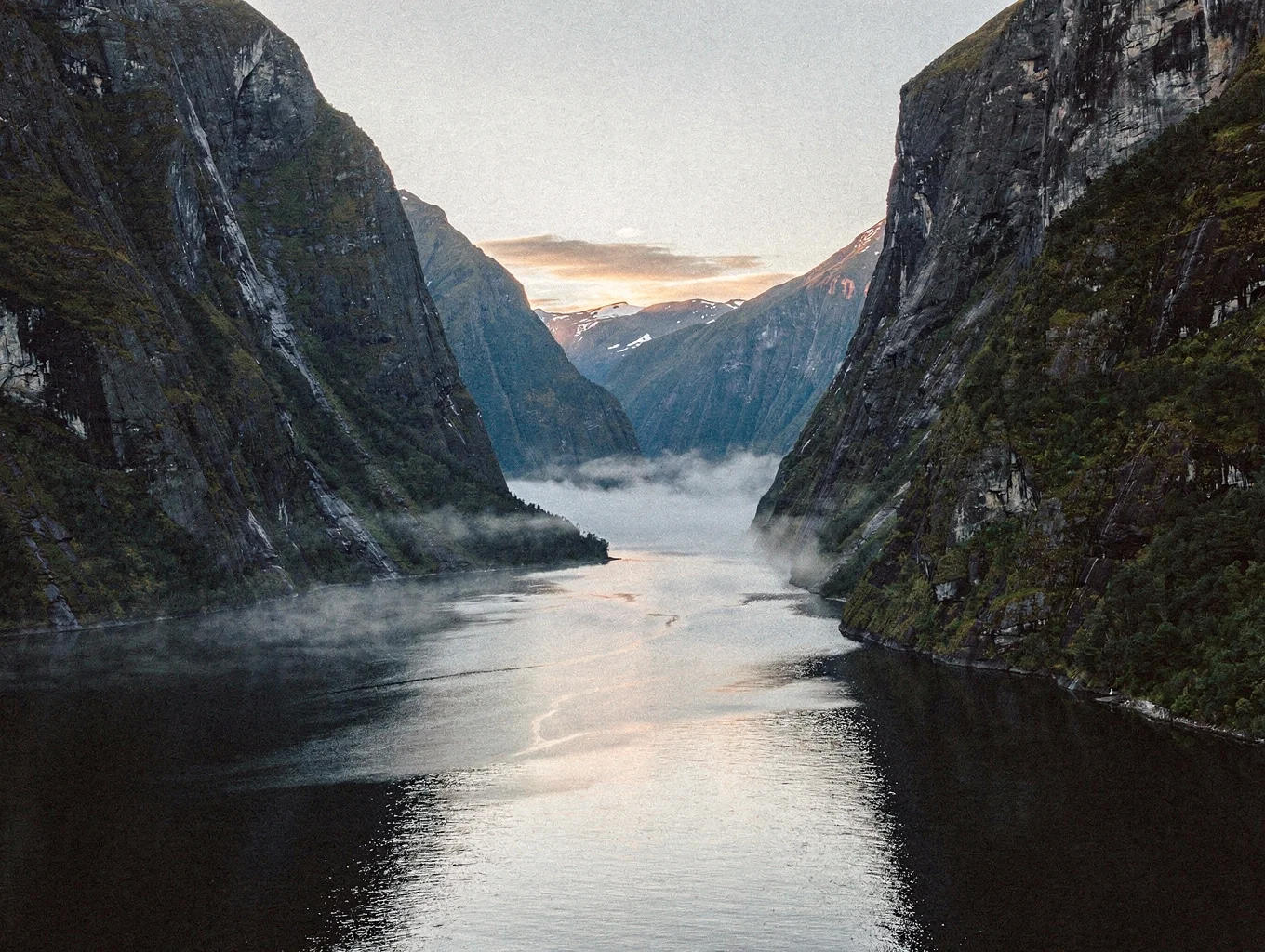 Moody cliffs rising above dark fjord waters
